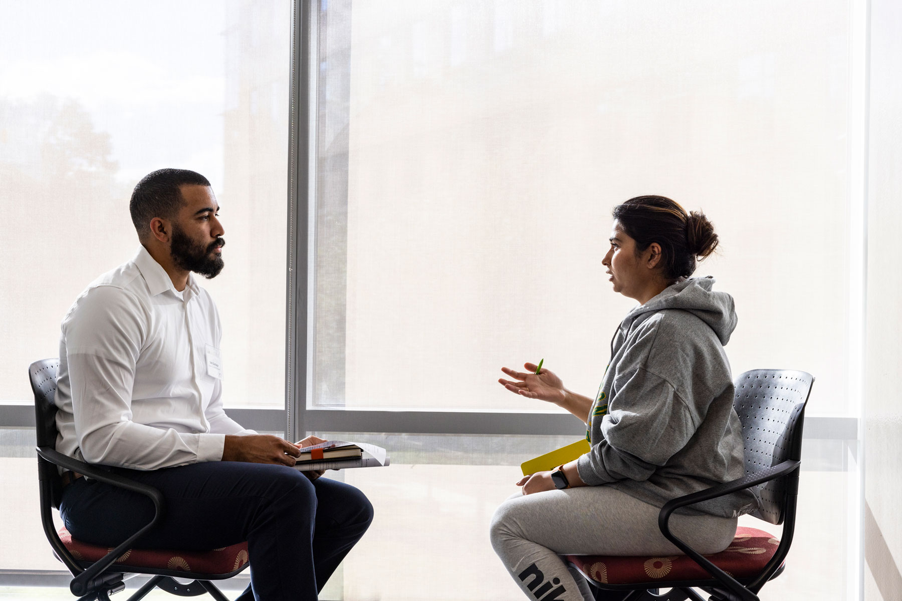 A student seeks advice and input from a CEDRIC staff member. They are conversing across a cafe style table in a casual setting. 