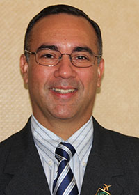 Paulo Costa wears a dark suit, striped tie, and glasses in his faculty profile for the Department of Cyber Security Engineering at Mason