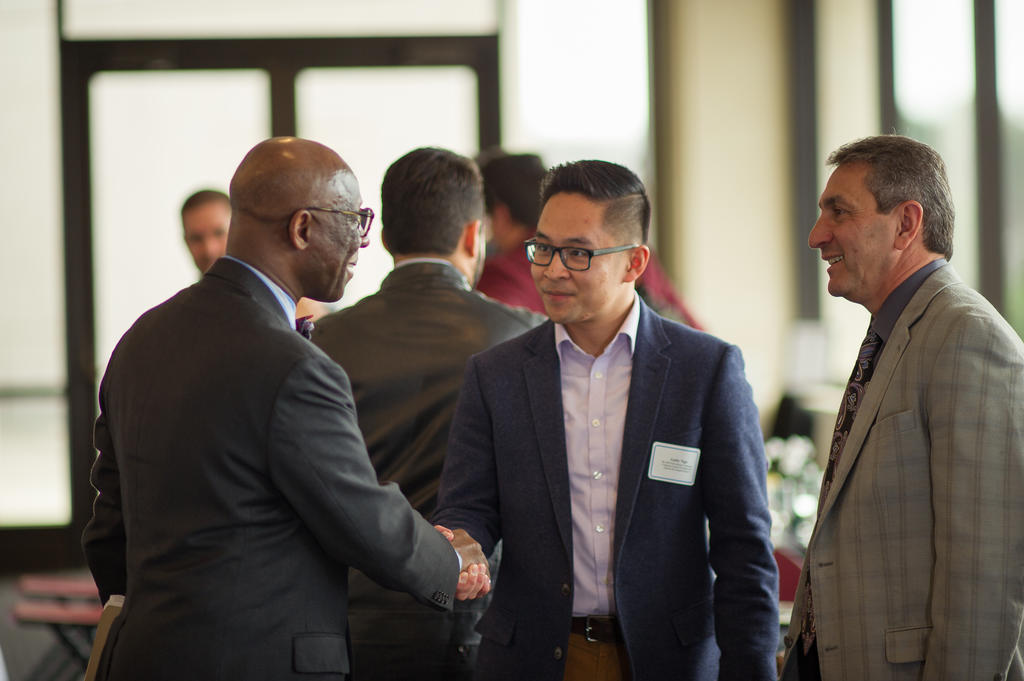 Alumni, faculty, and students networking in a room.