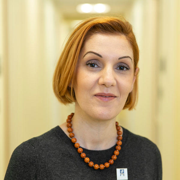 Amarda Shehu, professor in the CS department at Mason's College of Engineering and Computing, wears an orange necklace and dark-gray dress for her featured photo by Creative Services