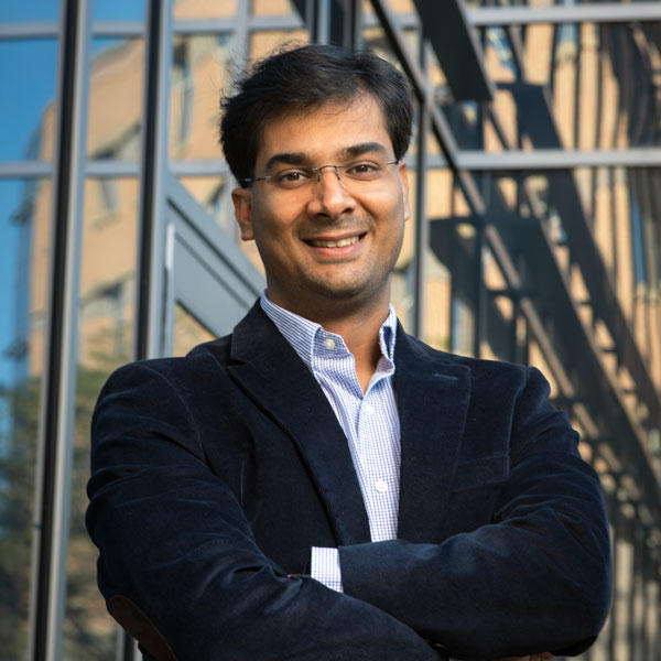 Hemant Purohit, associate professor in the IST department at Mason's College of Engineering and Computing, wears glasses and a dark-blue suit for his feature photo in front of the engineering building