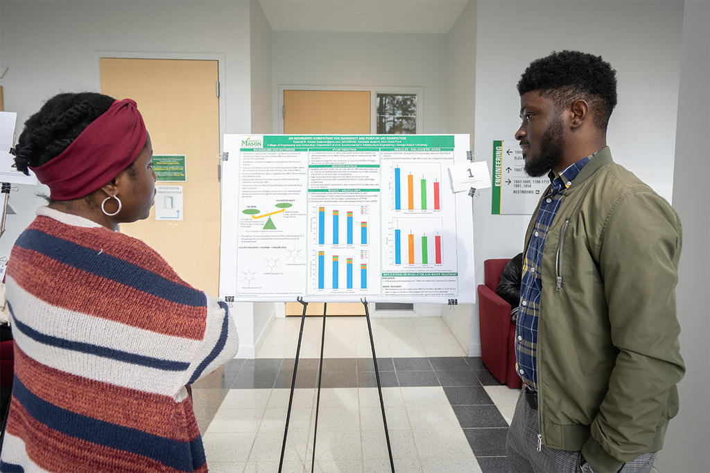 A black male graduate student presents his project to a black female employee