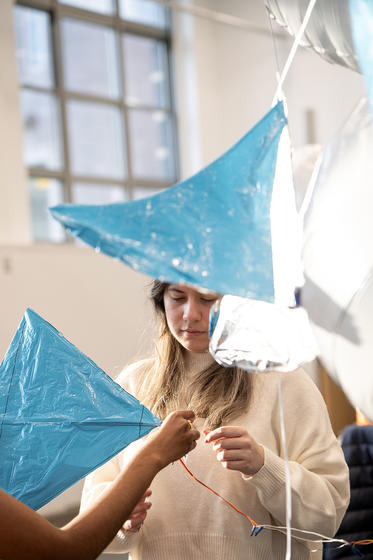 A female student constructs her blue mylar film blimp