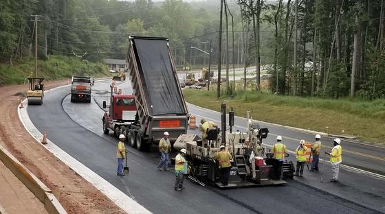 A construction site with workers putting down asphalt