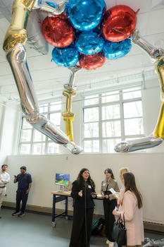 Students stand under a lighter-than-air "blimp" resembling an arcade claw