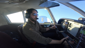 A man flying a small plane, with a view from inside the cockpit