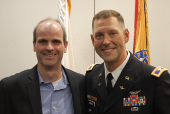 Two men pose, with the one on the right in military dress