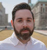 Mason assistant professor Johnathan Auerbach wears a white, collared-shirt and has brown hair and a beard in his faculty profile