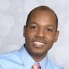 Archange smiles in his profile photo wearing a blue, collared shirt