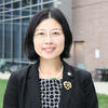 Guiping Hu wears glasses, a plaid dress and smiles